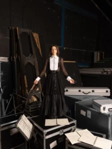 Directora de orquesta sobre cajas de transporte en el backstage de un teatro. Producción audiovisual de nuestra agencia de contenido.