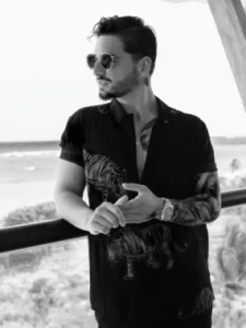 Fotografía en blanco y negro de Maluma con camisa de tigre en un balcón tropical. Creación de impacto visual por nuestra agencia de contenido.